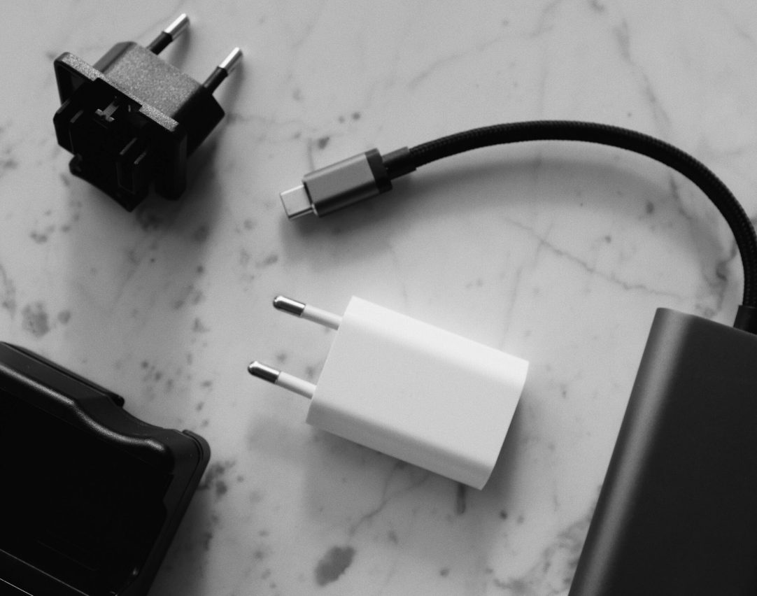 Composition of various modern charging units with adapter and small black external battery with short cable placed on white marble table